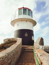 Lighthouse by sea against sky