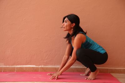 Young woman crouching by wall