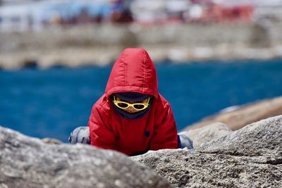 Playful boy in warm clothing at lakeshore