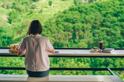 Rear view of woman sitting on table