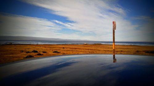 Reflection of clouds on vehicle hood at beach