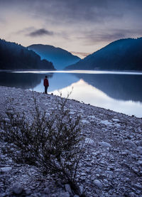 Man on lake against sky during sunset