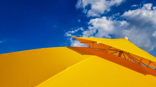Low angle view of yellow parasol against sky