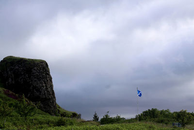 Flag by cliff against sky