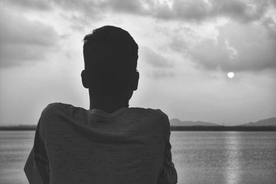 Rear view of man looking at sea against sky