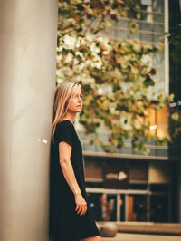 Side view of woman looking away while leaning on column