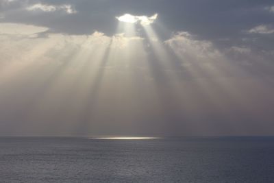 Sunlight streaming through clouds over sea