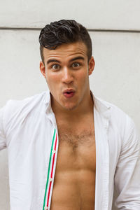 Portrait of young man standing against wall