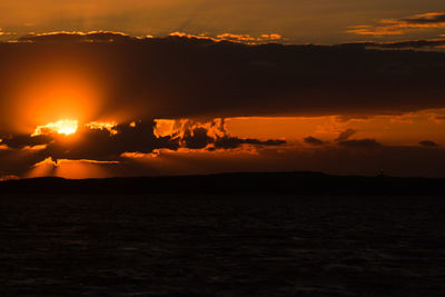 Scenic view of sea against dramatic sky during sunset