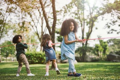 Happy friends playing tug-of-war at park