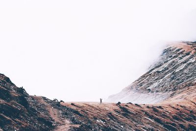 Distant view of man walking on mountain during winter