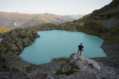 Man on rock by mountains against sky