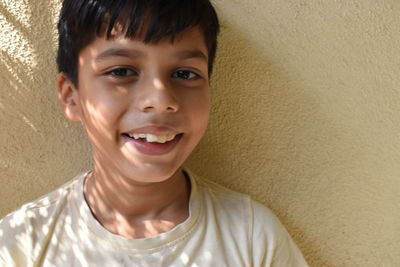 Portrait of a smiling young woman against wall