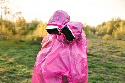 Couple with vr glasses and raincoat while standing on field