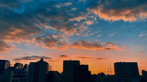 Modern buildings against dramatic sky during sunset