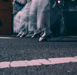 Low section of woman walking on road in city