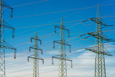 Low angle view of electricity pylon against blue sky