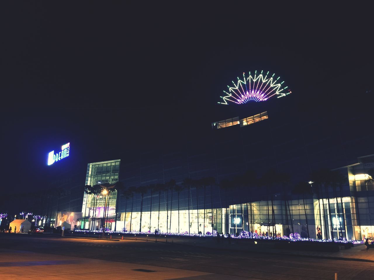 ILLUMINATED FERRIS WHEEL BY BUILDING AT NIGHT