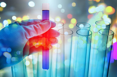 Cropped hand of scientist examining blue chemical in laboratory