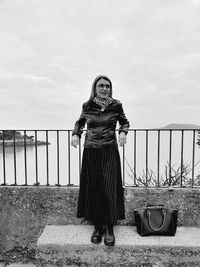 Portrait of woman standing against railing