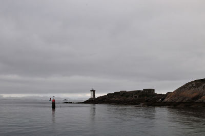 Lighthouse by sea against sky