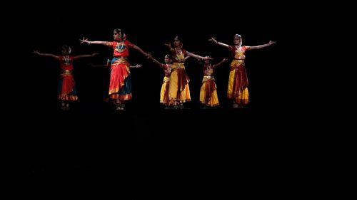 Group of people dancing against black background