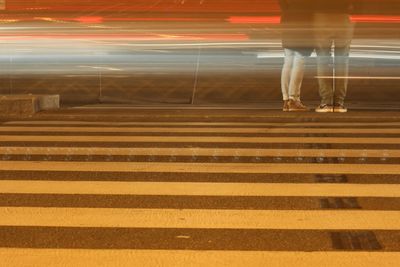 Blurry light trails and couple standing at zebra crossing