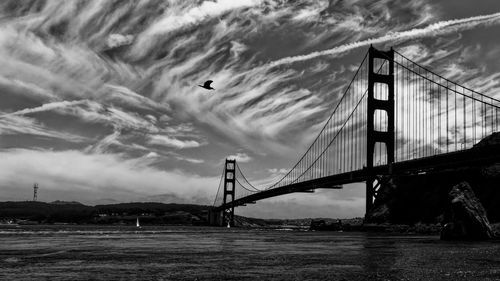 View of suspension bridge against cloudy sky