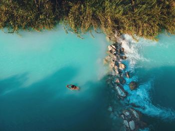 Aerial drone view of man swimming in tropical blue hot springs river