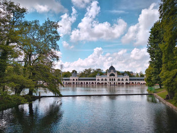 View of building by river against cloudy sky