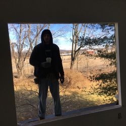 Man photographing against sky seen through window