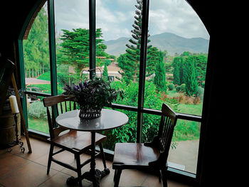 Empty chairs and table against trees seen through window