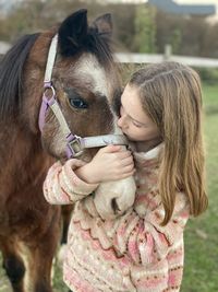 Girl giving kisses to her pony.