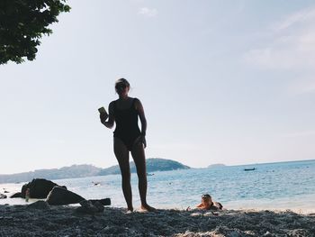 Rear view of woman and daughter on beach