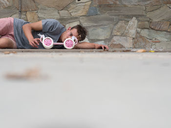 Portrait of young depressed man with toy lying on footpath