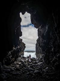 People on beach by rock formation against sky