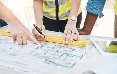 Midsection of man working on blueprint