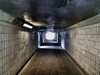 Empty walkway in illuminated tunnel