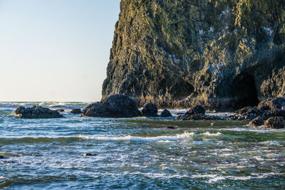 Rock formation in sea against clear sky