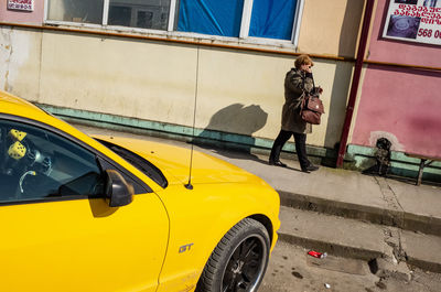 Man standing by yellow car in city