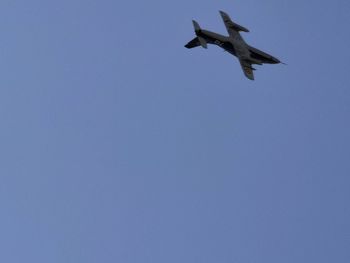 Low angle view of airplane flying against clear blue sky