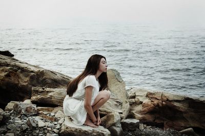 Woman sitting on rock at sea shore