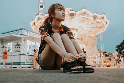 Full length of woman sitting in city against sky