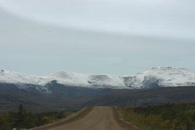 Road leading towards snowcapped mountain against sky