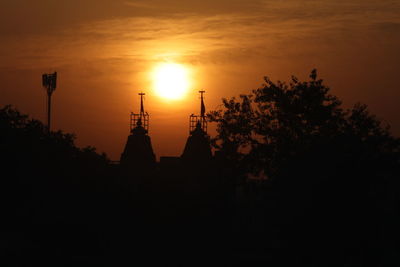 Silhouette trees and buildings against sky during sunset