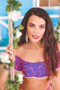 Portrait of beautiful woman sitting on swing with flowers