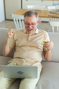 Portrait of young woman using laptop while sitting on sofa at home