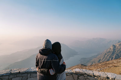 Rear view of man standing on mountain against clear sky