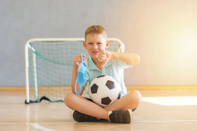 Portrait of smiling boy with ball on floor