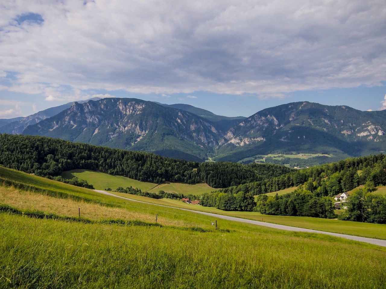 mountain, tranquil scene, landscape, tranquility, sky, scenics, mountain range, beauty in nature, nature, grass, cloud - sky, field, green color, tree, growth, cloud, non-urban scene, cloudy, idyllic, rural scene